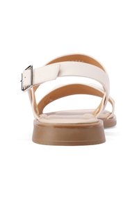 Sandali beige chiari con tomaia in pelle liscia, design delle cinghie sottile, fibbia metallica e suola bassa in gomma marrone.