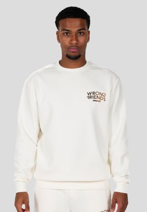 Sudadera blanca de canalé con un pequeño logo marrón "WRONG FRIENDS" en el pecho. Cuello redondo y mangas largas.