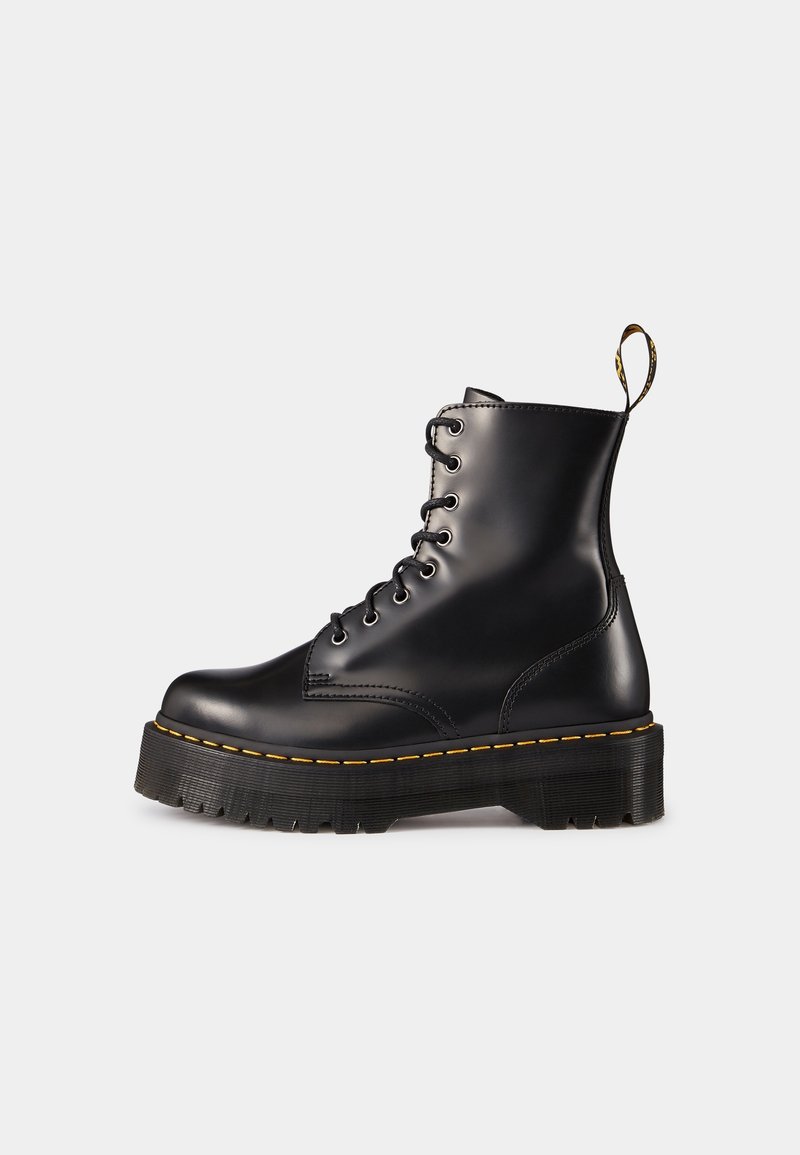 Botte de combat noire en cuir à lacets avec semelle épaisse rainurée et détail de coutures jaunes, vue de côté sur fond clair.