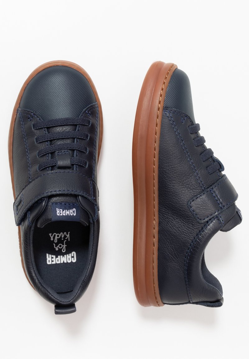 Jūras zilas ādas sporta kedas ar brūniem gumijas zole, ar auklām un Velcro siksniņu aizdarei, teksturēta virsma un kontrastējoša šuvuma elementi.