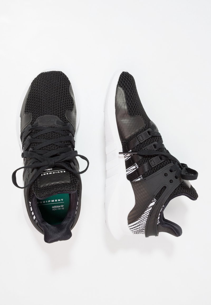 Svarta träningsskor med överdel av mesh och syntetmaterial, vit sula, texturerade detaljer och svarta snören. Har en märkesinläggssula och unika designelement.