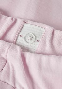 Ανοιχτό ροζ ύφασμα με υφασμένο λάστιχο στη μέση, λευκή ελαστική ταινία και λεπτομέρεια από διάφανο πλαστικό κουμπί. Μαλακή υφή και αόρατες άκρες.