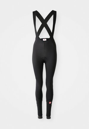 Salopette da ciclismo nera imbottita con spalline incrociate e un piccolo logo rosso sulla parte inferiore della gamba su sfondo bianco.