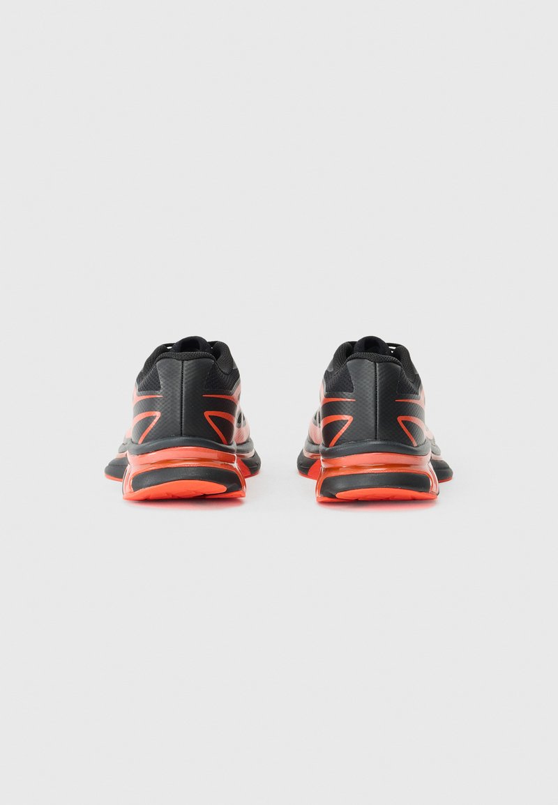 Baskets de sport noires avec des accents orange, tige en mesh, bout rond, semelle texturée et col rembourré, vues de l'arrière.