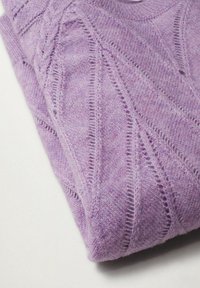 Pull en maille lavande plié avec des motifs ajourés diagonaux et des torsades, posé sur une surface blanche.