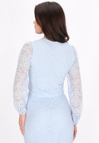 Rochie dantelată bleu deschis, cu mâneci lungi transparente și modele florale, cu talie ajustată și accente de nasturi pe mâneci.