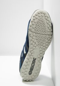 Baskets pour hommes bleu marine avec dessus en tissu, semelle en caoutchouc et motif de bande de roulement circulaire. Présentent le logo de la marque sur la semelle et des accents de ventilation.