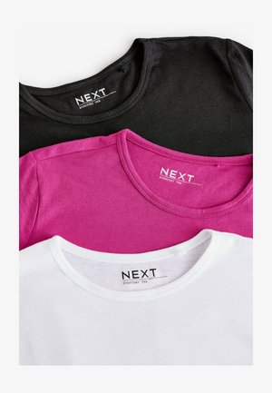 Kolm T-särki on laialt laotatud: must, fuksia ja valge. Kõigil on ümmargune kaelus ja musta tekstiga silt "NEXT EVERYDAY TEE".