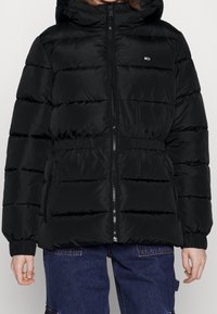 Giubbotto imbottito nero con cappuccio, chiusura con zip, vita e polsini elasticizzati. Presenta cuciture orizzontali a baffle e tasche laterali.