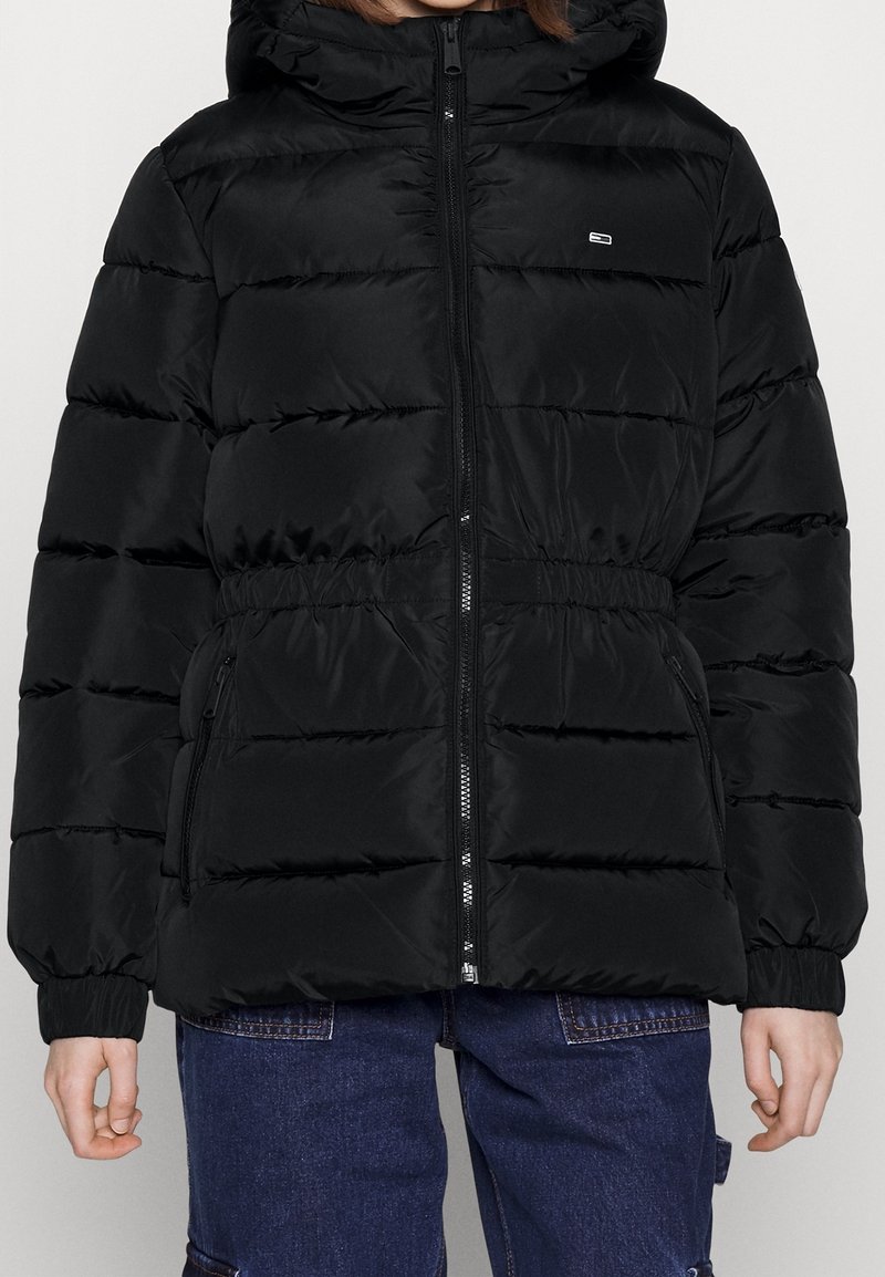 Giubbotto imbottito nero con cappuccio, chiusura con zip, vita e polsini elasticizzati. Presenta cuciture orizzontali a baffle e tasche laterali.