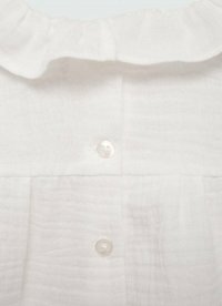 Valkoinen, teksturoitu kangas, jossa on rypytetty kaulus. Edessä on kaksi läpinäkyvää nappia, joita täydentävät hienot vaakasuorat laskokset.