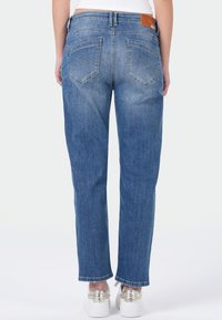 Lichtblauwe denim jeans met een relaxte pasvorm, voorzien van twee achterzakken, vervaagde secties en een bruine leren patch op de taille.