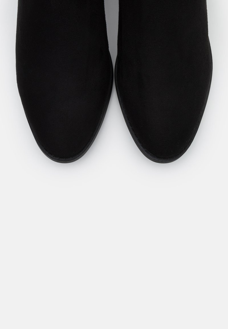 Schwarze Wildleder-Ankle-Boots mit spitzem Zeh, glatter Textur und minimalistischem Design. Keine sichtbaren Beschläge oder Akzente, durchgehend einfarbig.