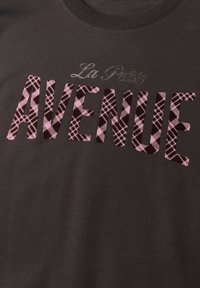 Tissu foncé avec le texte "La Petite" en petites lettres cursives et grandes lettres à motif à carreaux formant "AVENUE" en rose et noir.