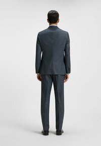 Donkerblauw patroonpak met een op maat gemaakte pasvorm, voorzien van een enkele split en bijpassende broek. Soepele textuur en gestructureerd ontwerp.