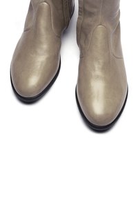 Stivaletti alla caviglia in pelle grigia con texture liscia, punta appuntita e dettagli di cuciture minime. Suole in gomma nere per garantire la durabilità.