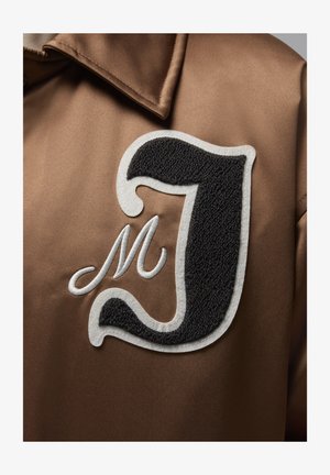 Brown satin jacket featuring an embroidered black letter "J" with white outlines, and an additional stylized white "M" detail.