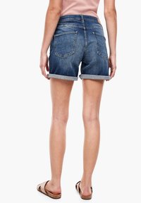 Shorts en denim bleu foncé avec des revers, comportant deux poches arrière, une texture lisse et une taille standard.