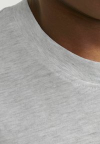 Camiseta de algodón gris con cuello redondo acanalado, textura suave y un sutil patrón jaspeado, mostrando un primer plano del área del cuello y los hombros.