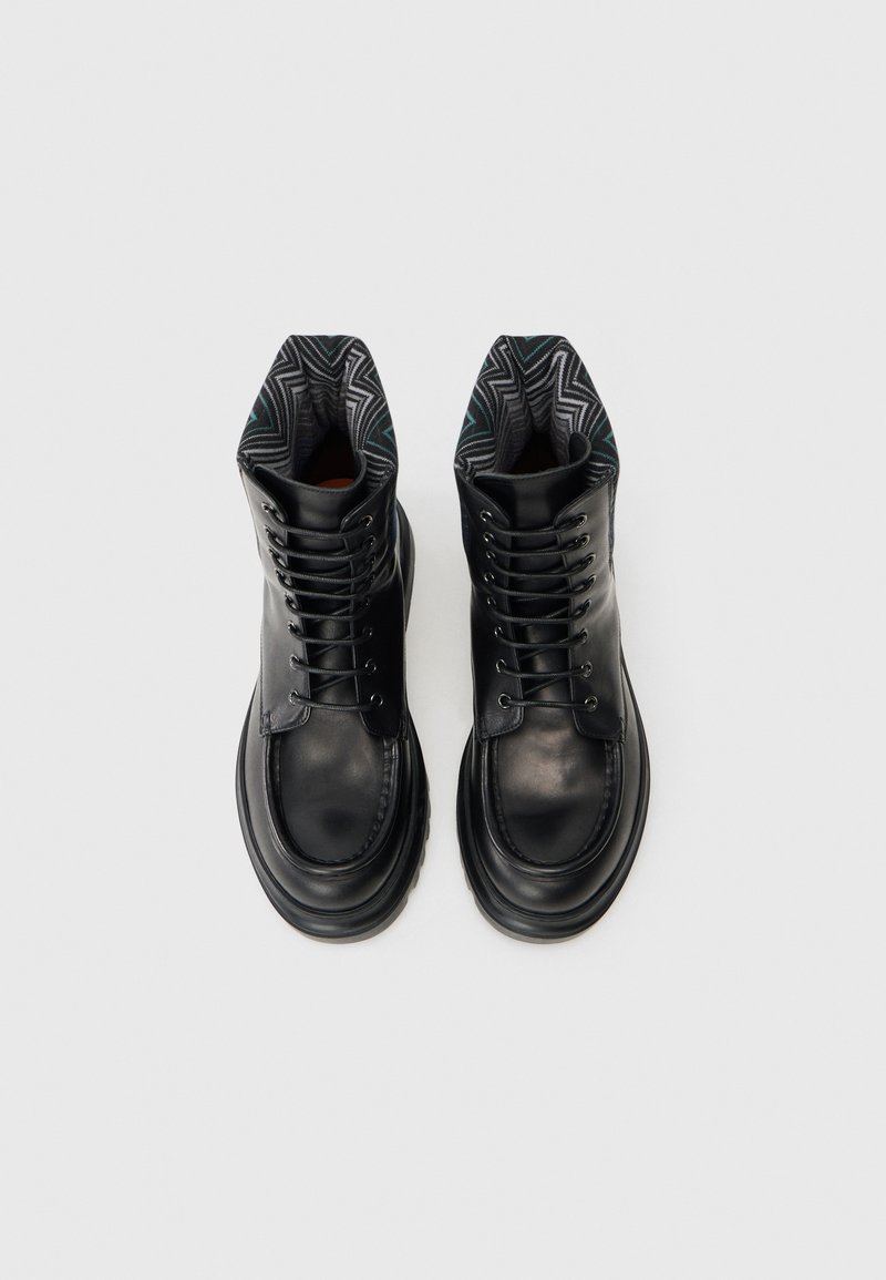Sorte læderankelstøvler med rund tå, snøresystem og mønstret tekstilforing med geometriske designs.