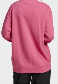 Rosa sweatshirt med avslappnad passform, sänkta axlar och ribbade manschetter. Slät textur, rund halsringning och låg nederkant.