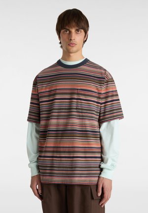 Camiseta de rayas en varios colores, con cuello redondo, mangas cortas y un bolsillo en el pecho; llevada sobre una camiseta de manga larga de color azul claro.