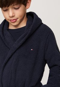 Marineblauwe fleece badjas met een gestructureerde afwerking, voorzien van een capuchon en een klein logo label op de borst.
