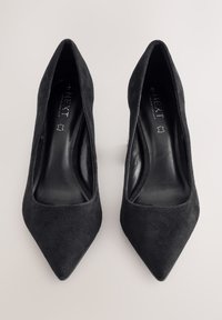 Crne antilop visoke potpetice sa špicastim vrhovima, glatkom unutarnjom postavom i minimalističkim dizajnom. Bez vidljive metalne opreme ili uzoraka.