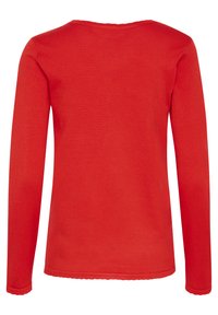T-shirt à manches longues en coton rouge uni, avec un col rond et un ourlet en forme de vagues. Texture lisse sans motifs ni accents visibles.
