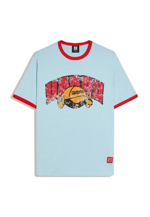 Svetlomodré tričko so červeným golierom a lemami rukávov, s poškodenou červeno-žltou kruhovou grafikou s textom a malou červenou značkou na okraji.