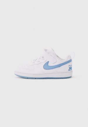 Baskets pour tout-petit blanches avec le swoosh Nike bleu clair, une bride à Velcro, et un détail d'ours en peluche bleu sur le talon, vues de profil.