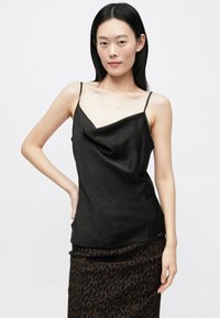 Zwarte satijnen camisole met een watervalhalslijn en dunne bandjes, met een getextureerd oppervlak en subtiele patronen, gecombineerd met een panterprint rok.