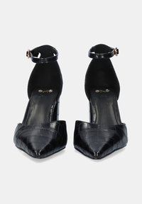 Tacones altos negros con tira al tobillo, punta afilada, textura de cocodrilo y un pequeño detalle en dorado en la hebilla de la tira. Suela interior negra plana.