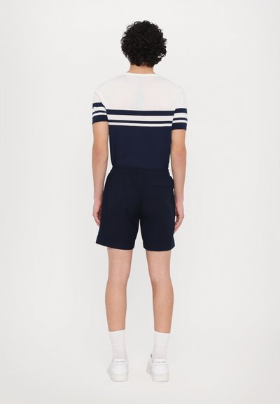 T-shirt bleu marine avec des rayures horizontales blanches, associé à un short bleu marine. Le short dispose d'une taille élastique et d'une poche arrière.