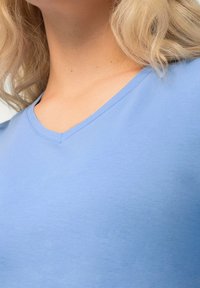 Ljusblå V-ringad t-shirt gjord av mjukt bomullsmaterial, med en jämn textur och en elegant halsdesign.