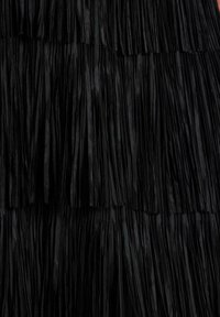 Tela de flecos negra con tiras texturizadas en capas. Cada capa presenta longitudes variadas, creando una apariencia ondulada a lo largo del material.