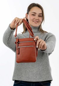 Borsa a tracolla in pelle color ruggine, con due tasche frontali zip, tracolla corta e texture liscia.