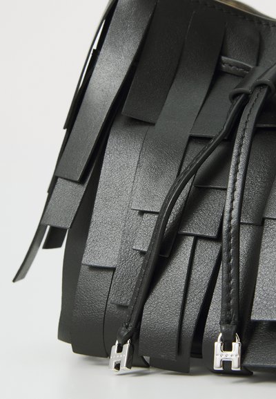 Sort lædertaske med et vævet frynsedesign, glat tekstur og sølvfarvede hardwaredetaljer. Justerbare stropper er synlige.
