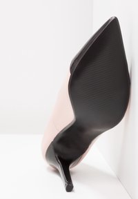 Rosa syntetisk stilettklack med spetsig tå och svart sula; slät yta med glänsande finish; 10 cm hög klack.