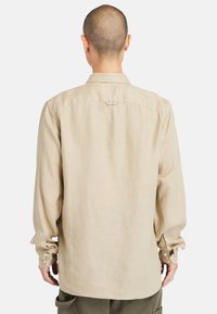 Beige overhemd met lange mouwen van gestructureerde stof, voorzien van een standaardkraag, knoopmanchetten en een rechte zoom.