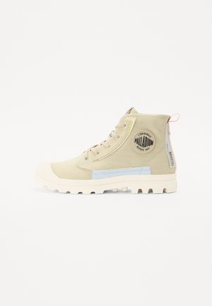 Beige hoge sneakers van canvas met een rubberen neus en een gestructureerde zool. Heeft een blauwe accentstrook en een logopatch aan de zijkant.