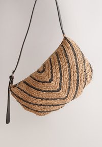 Borsa a tracolla in paglia intrecciata con una forma curva, caratterizzata da un motivo a spirale, toni neutri e una cinghia in pelle nera.