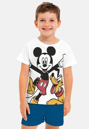 Young boy smiling, wearing a white t-shirt with Mickey Mouse and Pluto graphics, paired with blue shorts, standing against a plain background.