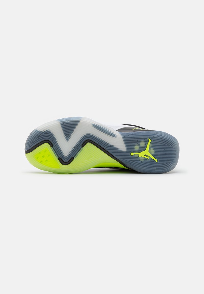 Suela de zapato de material gomoso, con un patrón en zigzag en azul, blanco y verde brillante, con un acento negro y detalle de logo.
