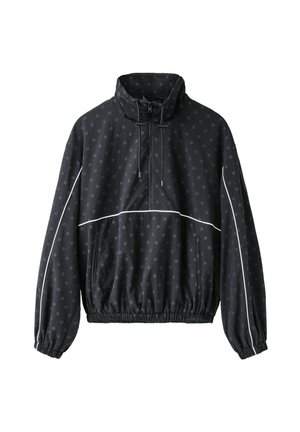 Pull noir à pois subtils, fermeture éclair sur le devant, col à cordon, poignets élastiques, passepoil blanc sur les manches et la poitrine.