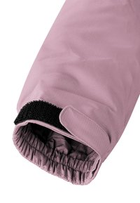 Ärmel einer pinkfarbenen isolierten Jacke mit strukturiertem Stoff, elastischem Bund und einem schwarzen Klettverschluss für einen sicheren Sitz.
