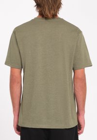 Camiseta de manga corta color verde oliva, con escote redondo, textura suave, corte relajado, sin patrones ni acentos visibles en la vista trasera.