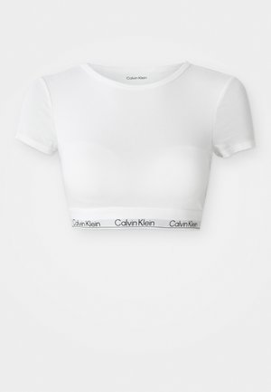 White short-sleeve crop top with crew neck and Calvin Klein logo on the elastic band at the waist.