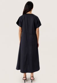 Black, ankle-length dress with short sleeves and a relaxed fit, featuring a simple design and a subtle seam detail along the back.