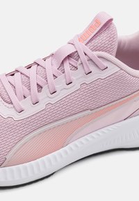 Scarpa da ginnastica rosa chiaro con tomaia in rete testurizzata, chiusura con lacci piatti e intersuola bianca; presenta un discreto design a righe sul lato.